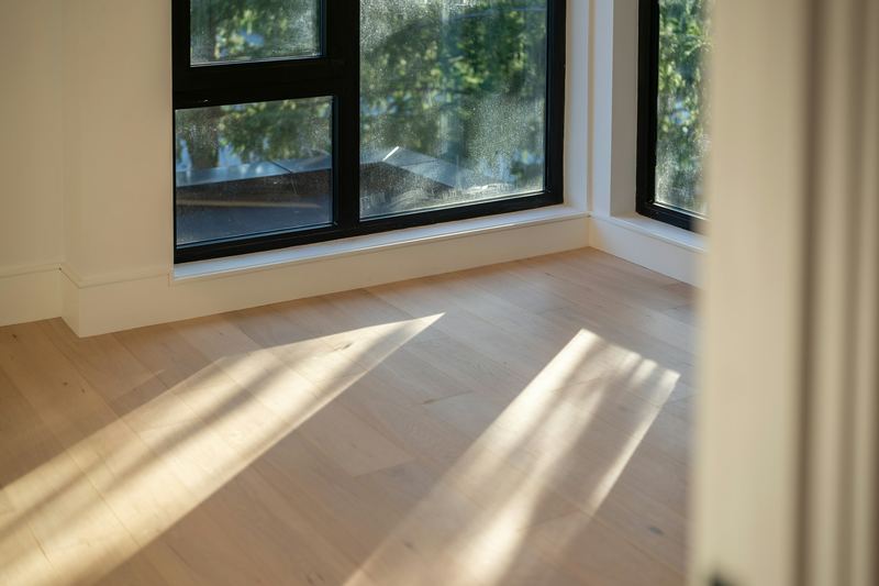Sunlight across light oak floorboards in an empty room