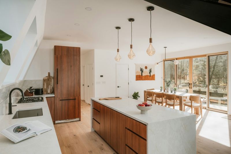 Bright kitchen with walnut cabinetry, a stone island, and pendant lights