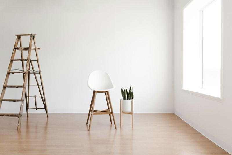 Freshly painted white room with a wooden ladder and stool